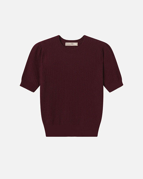 Flat lay of a short-sleeve textured knit top in deep burgundy with a ribbed hem and crew neckline, displayed against a white background.