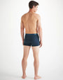 A full body backside image of a shirtless man wearing navy blue boxer briefs with nautical knots print along the waistband. The background is white.