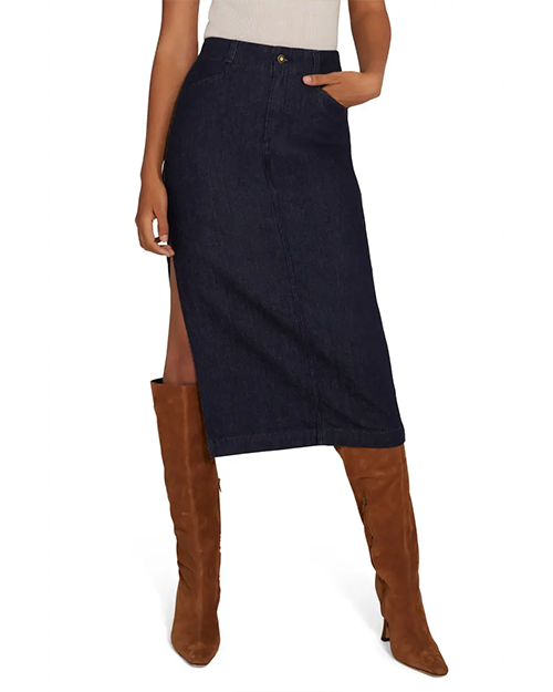 A lower body view of a model wearing a white shirt tucked into a dark blue denim skirt with a high slit on the side, paired with brown suede knee-high boots. The background is plain white.