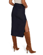 The backside view of a model's lower body wearing a white shirt tucked into a dark blue denim skirt with a high slit on the side, paired with brown suede knee-high boots.