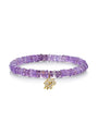 A transparent purple beaded bracelet with a gold flower pendant adorned with jewels. The background is plain white.
