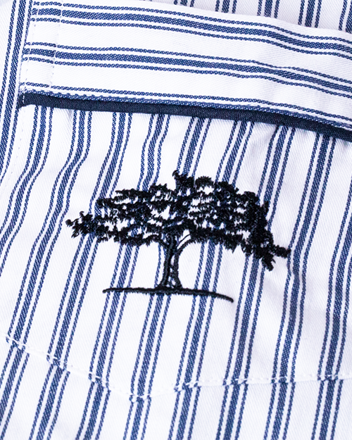 A close-up view of blue and white striped fabric with a pocket and an embroidered navy tree.