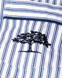 A close-up view of blue and white striped fabric with a pocket and an embroidered navy tree.