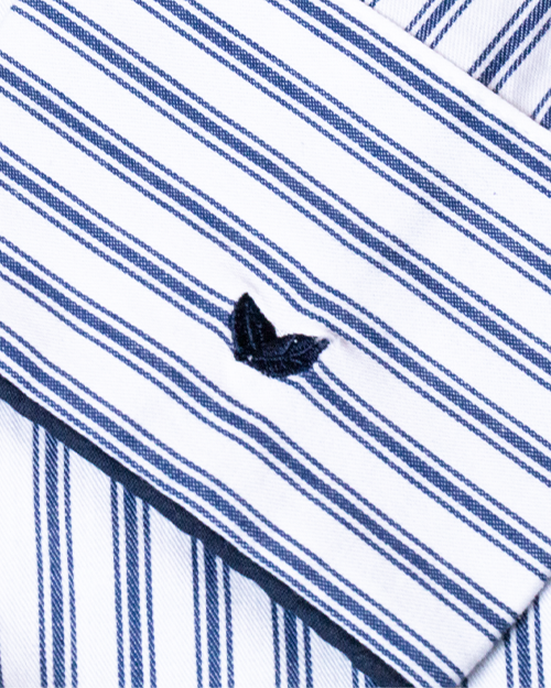 A close-up view of blue and white striped fabric with two small navy embroidered leaves.
