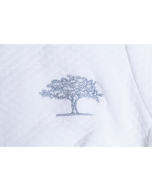 A close-up image of a white diamond patterned fabric with a grey embroidered tree.