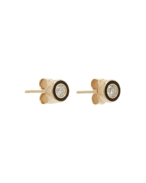 A sideview of a pair of gold stud earrings with a black enamel circular design and a diamond in the middle, angled to show butterfly earring backings attached. The background is plain white.
