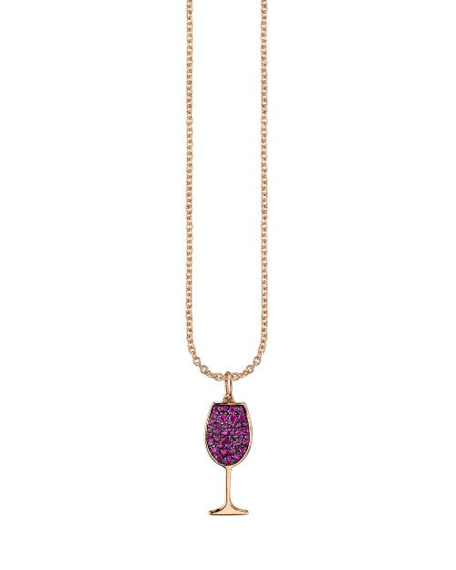 A rose gold chain with a wine glass pendant adorned with purple gems. The chain is hanging over a white background.