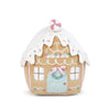 A plush toy gingerbread house with white icing-like decorations on it, behind a white background. The roof is topped with sprinkles a peppermint decoration.