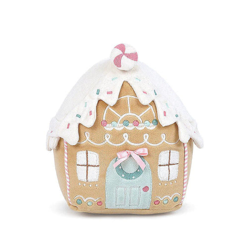 A plush toy gingerbread house with white icing-like decorations on it, behind a white background. The roof is topped with sprinkles a peppermint decoration.