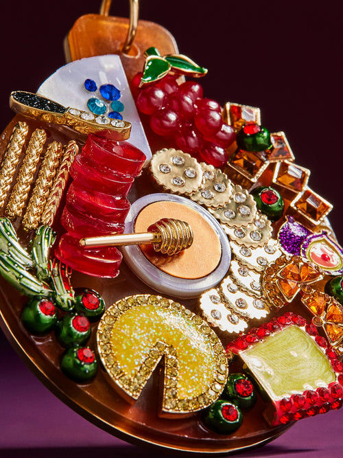  A decorative Christmas ornament showcasing a variety of food items, such as candies, fruits, and holiday snacks