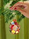 A hand displays a Christmas ornament adorned with food illustrations, blending culinary themes with festive ornamentation.