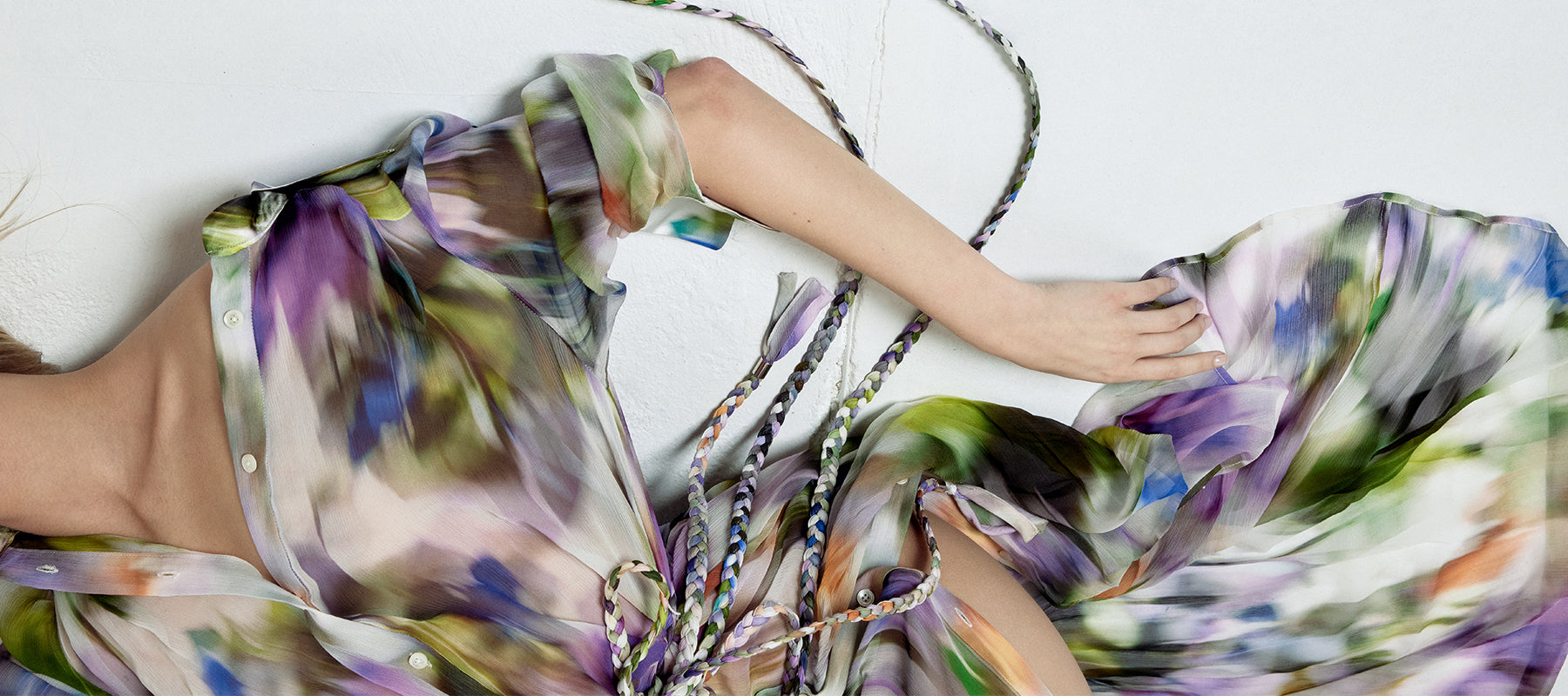 Multicolored floral dress on a person laying on a white background.