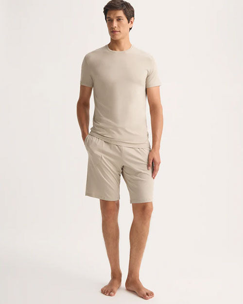 A model showcases a casual outfit featuring a beige t-shirt paired with shorts, ideal for warm weather.
