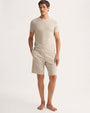 A model showcases a casual outfit featuring a beige t-shirt paired with shorts, ideal for warm weather.