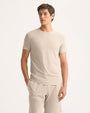 A model showcases a casual outfit featuring a beige t-shirt paired with shorts, ideal for warm weather.