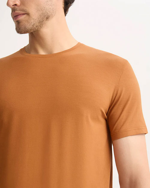 A man in an orange t-shirt is seen, reflecting a laid-back and casual appearance.