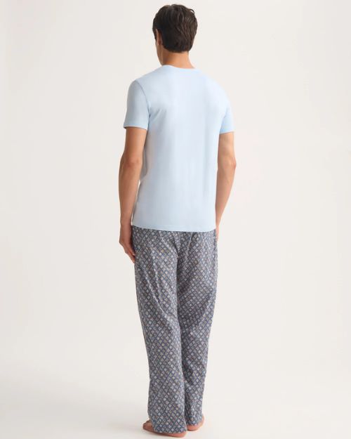 The back view of a man wearing a light blue T-shirt and patterned pants, showcasing a blend of comfort and understated elegance.