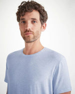 An upper body image of a man wearing a light blue short-sleeve t-shirt