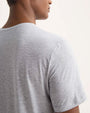 Rear view of a man in a grey t-shirt, standing casually with his arms relaxed at his sides.