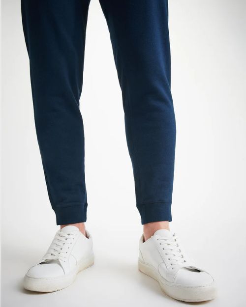 The image is of the bottom part of navy-blue joggers, and white shoes.