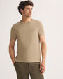 A model wearing a taupe t-shirt and khaki pants, standing against a neutral background.