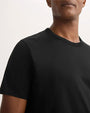 A man dressed in a black t-shirt poses, reflecting a simple and modern fashion choice.