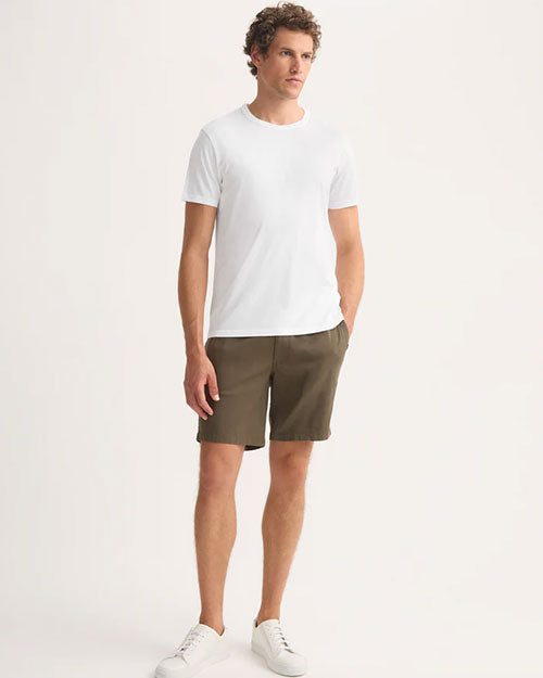 The model showcases a casual look in shorts and a white t-shirt, highlighting a simple style.