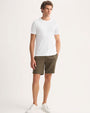 The model showcases a casual look in shorts and a white t-shirt, highlighting a simple style.
