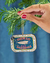 A hand holding a Christmas tree ornament shaped like smoked sardines, adding a unique touch to holiday decorations.