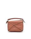 The image displays the back view of a tan or light brown Loewe leather bag, showcasing a distinctive geometric pattern with stitched lines forming an ‘X’ shape on the back panel.