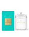 A product from Glasshouse Fragrances named ‘LOST IN AMALFI.’ The image shows a turquoise-colored packaging box on the left and a candle in a glass container with a lid on the right. The box indicates that it is a soy candle, weighing 380g or 13.4 oz.