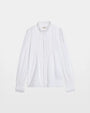 Photo of a white long-sleeved, button up blouse against a white background.