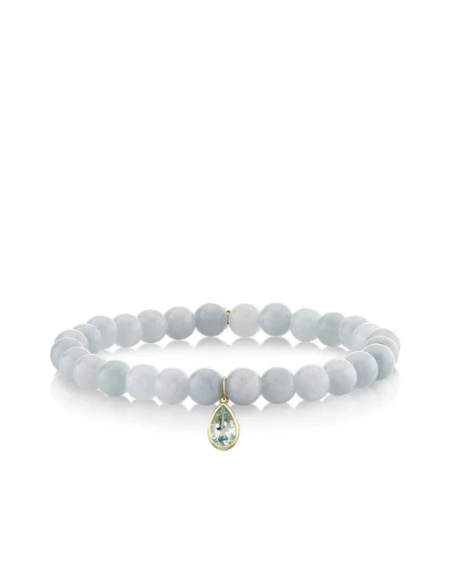 An image of a light blue beaded bracelet with a pear-shaped blue gemstone on a white background. 