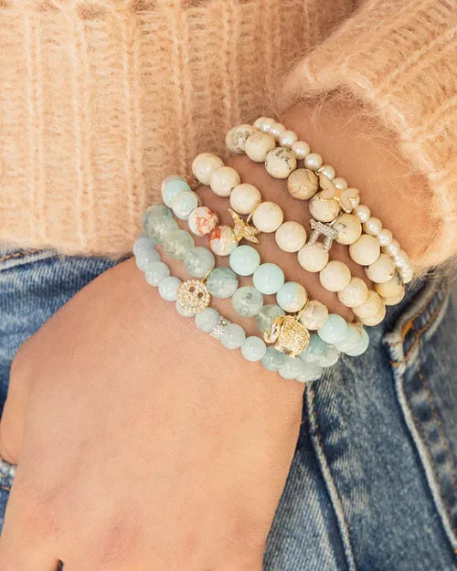 Image of an arm with multiple beaded bracelets. 
