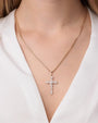 Close-up image of a model wearing a diamond encrusted gold cross necklace.