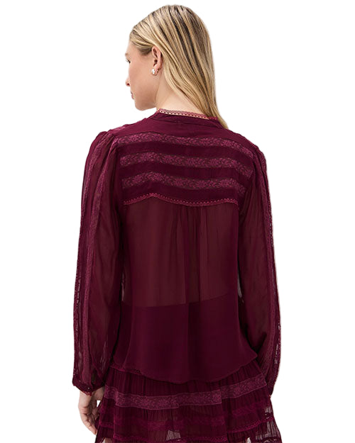 Back view of a person wearing a burgundy long-sleeved blouse with lace details and sheer fabric.