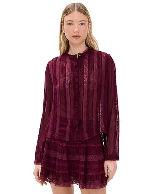 Person wearing a sheer, long-sleeved burgundy blouse with vertical lace stripes and front buttons, paired with a layered burgundy skirt featuring lace detailing.