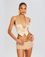 A nude satin low V-neck top. Top has a vest design with fake pocket stitching and three buttons. Model styles top with tan suede micro shorts and belt with gold hardware, and gold accessories.