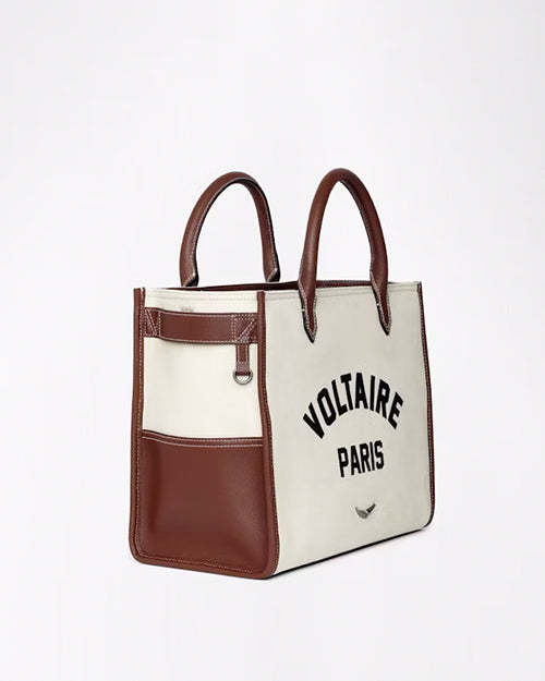 A side-view of a white double-strapped purse with brown detailing and the words 'VOLTAIRE PARIS' printed in the center in bold. The background is plain white.