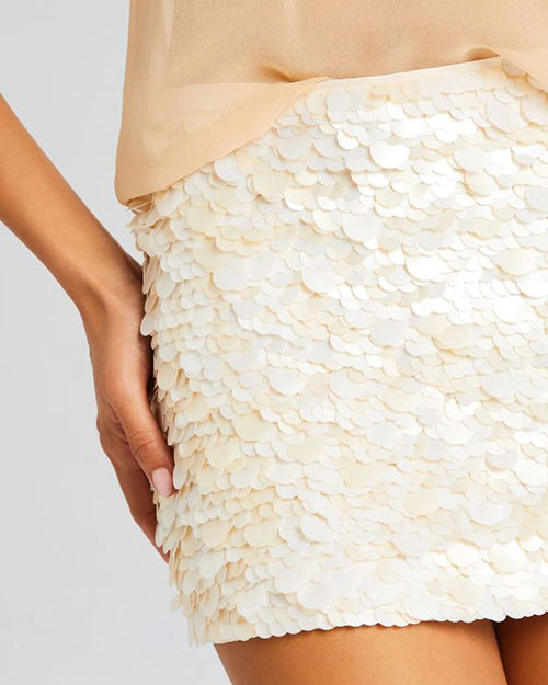 Close up of a sequin beige skirt on a person.