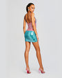 Back view of model in a mini sequined dress with a pattern that transitions from purple at the top to turquoise at the bottom. Dress has thin straps embellished with more sequence.