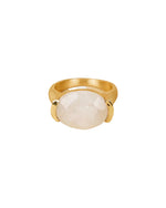 A gold ring featuring a large, oval-shaped white gemstone set in the center, secured by two prongs on either side.