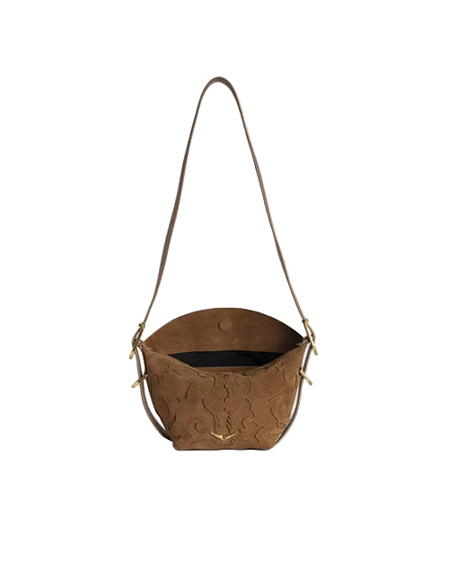 A brown suede handbag with a long strap, featuring an embossed floral pattern on the front, gold-tone hardware, and a black interior. The bag has a flap closure with a button.