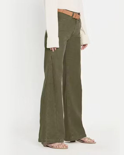 A side view of olive green denim trousers fitted around the hips with cinching detail mid leg that starts a wide leg fit at the bottom. The trousers have a smooth texture and are paired with a light brown belt with a gold buckle. The trousers are styled with a white top, partially visible, and nude open-toe sandals. The overall look is casual yet stylish, suitable for everyday wear.