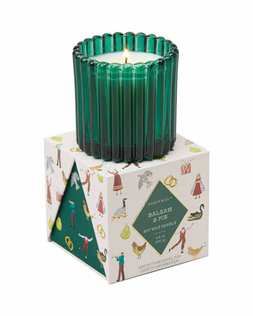 A green glass containing a candle, sitting on a decorative Christmas designed box.
