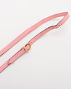 A pink shoulder strap with a gold-colored buckle with multiple holes for adjustment.