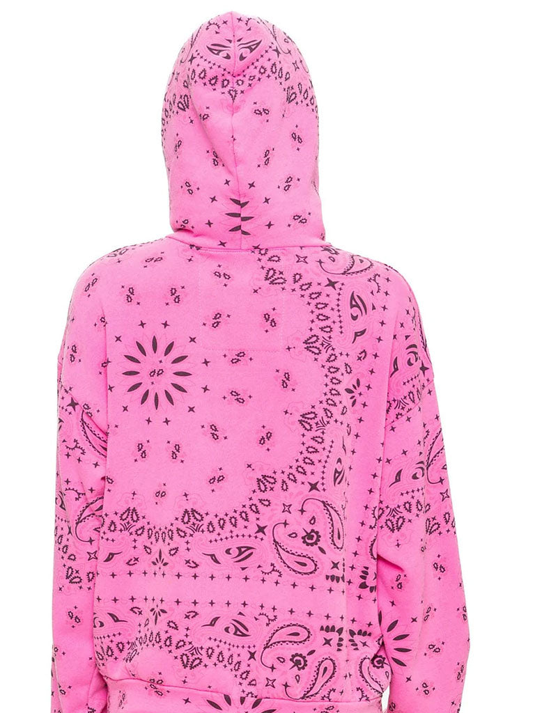 A person wearing a bright pink hoodie with a black bandana-style pattern is shown from the waist up. 