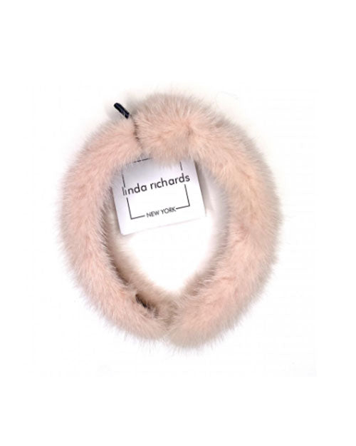 A blush mink fur headband with a knot in the middle. The label has black text that reads “linda richards NEW YORK.” 