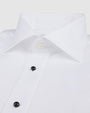 A close-up of a white dress shirt with black buttons down the front and one clear button at the top. The background is white.