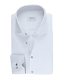An overhead view of a folded white dress shirt with grey buttons down the front and on the chest pocket. There is a white rectangular tag on the inner neckline. The background is plain.